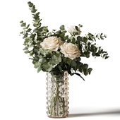 Bouquet of roses and eucalyptus branches in a tall glass vase with some pimples